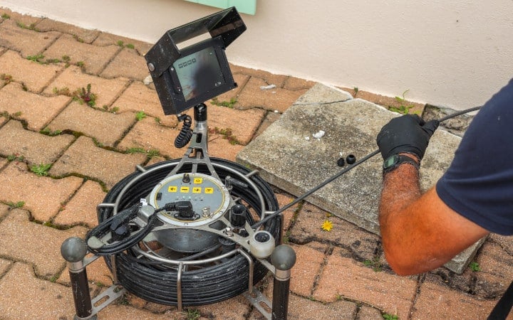 Technicien utilisant une caméra de contrôle pour nettoyage d'une canalisation bouchée